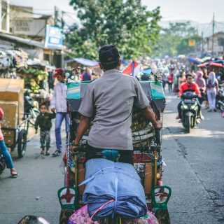 Energietransitie in Indonesië: een typische drukke straat met brommers, tuk-tuks en wandelende mensen langs marktkramen