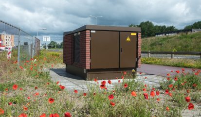 2024 06 12-Harderwijk, Netherlands: A new brown partly brick transformer house on the Piekegracht/Zuidwalstraat in the town of Harderwijk in Gelderland with various red poppies in the foreground..