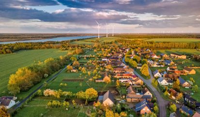 Aerial view over a little town with wind wheels and a lake in the background of a german countryside