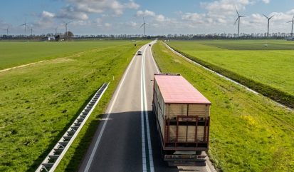 Vrachtwagen op de weg met in de verte windmolens