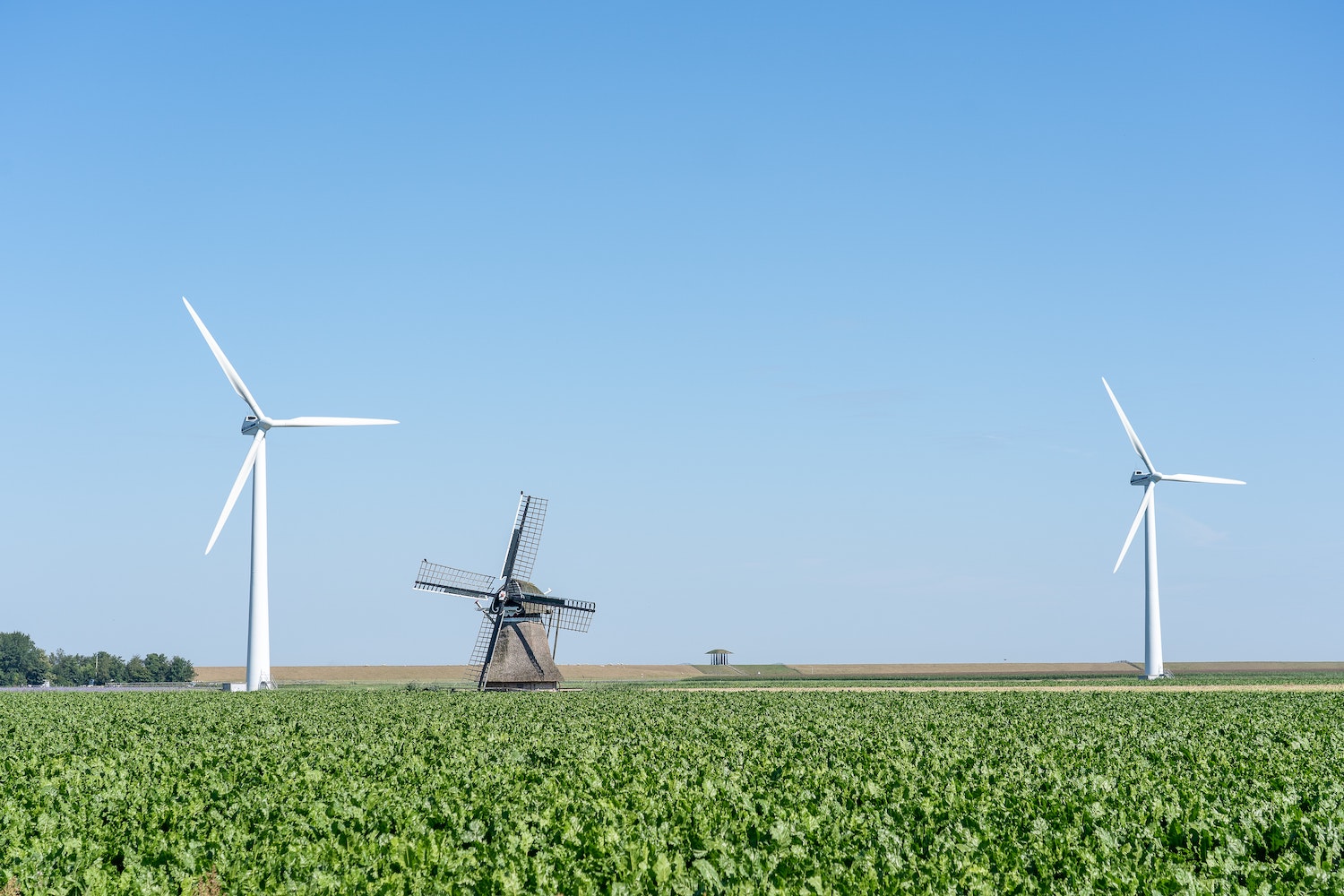 Illustratie van een hybride energiesysteem: twee nieuwe windmolens en een oud-Hollandse windmolen naast elkaar